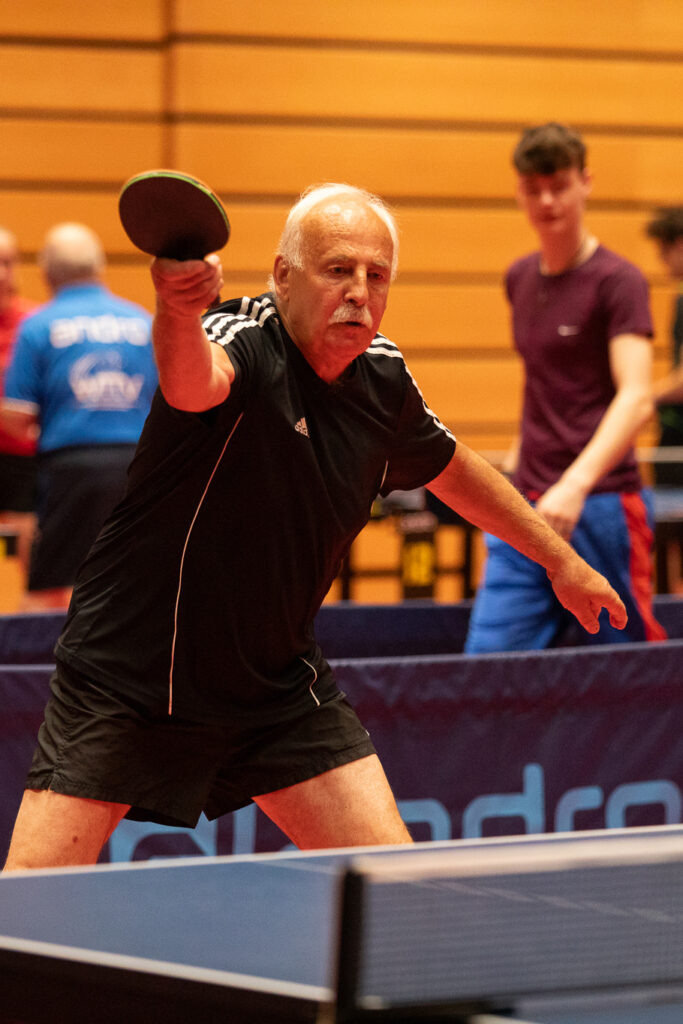 Älterer Mann spielt Tischtennis in der Halle
