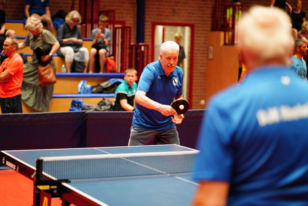 Ältere Männer spielen Tischtennis in einer Sporthalle