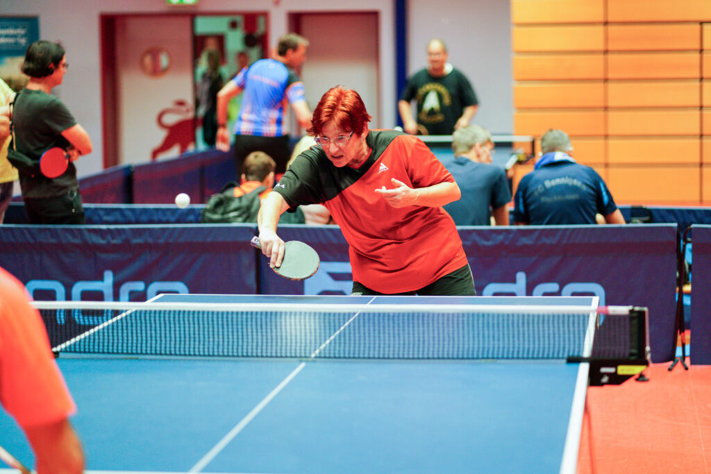 Frau mit rotem Shirt spielt Tischtennis auf Wettkampf