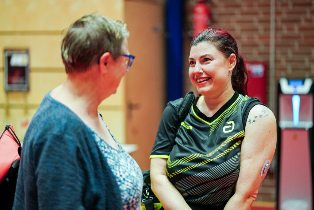 Zwei Frauen im Gespräch, eine in Sportkleidung mit Diabetes-Sensor