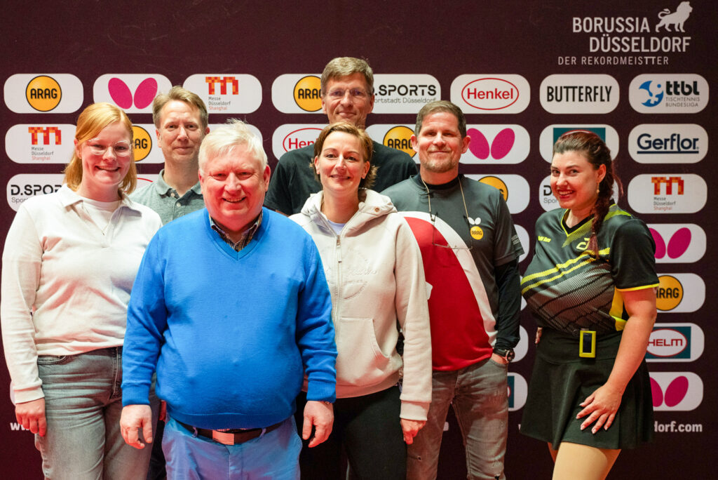 Gruppe von Menschen posiert vor gesponserten Markenschildern