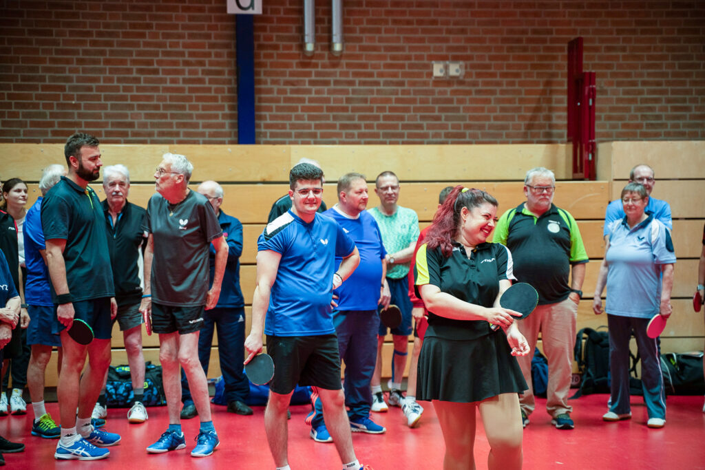 Menschen spielen Tischtennis in einer Sporthalle